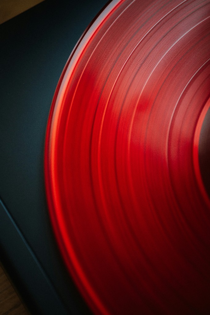 Translucent red vinyl on a turntable — analog listening and absolute fidelity.